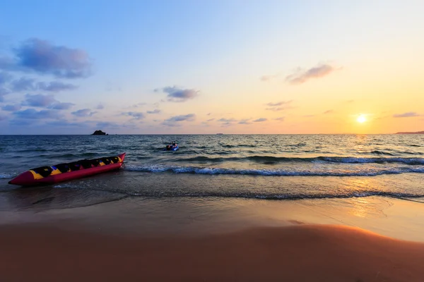Bananenboot en sleepboot in de zonsondergang — Stockfoto