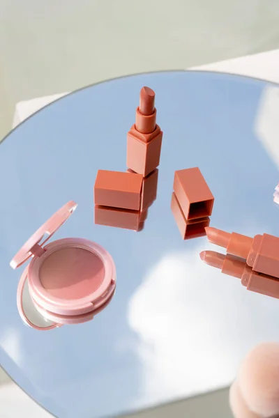 Cosmetic set: Lipstick and powder compact on circle mirror.