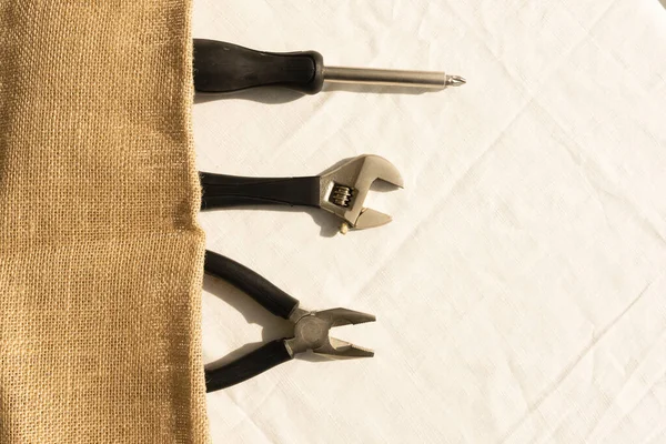 Set of different mechanic tools laying in a row on brown cloth. Top view.