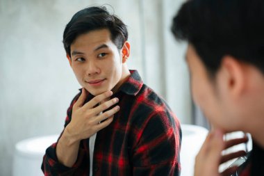 Asyalı genç bir adam bir kızla çıkmadan önce aynada kendine bakıyor..