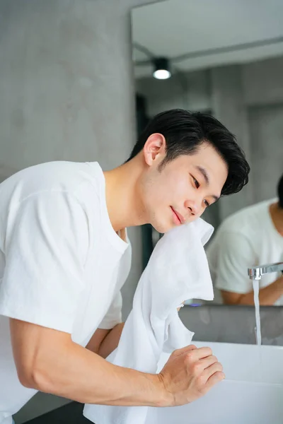 Азиатский Молодой Человек Стирает Убирает Лицо Полотенцем Ванной Комнате — стоковое фото