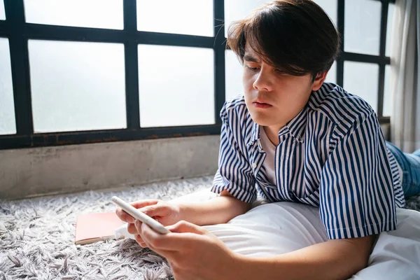 Asian young man playing mobile game on smartphone with serious looking.