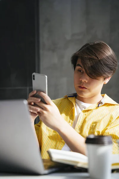 使用智能手机和笔记本电脑在家工作的亚洲年轻人 — 图库照片