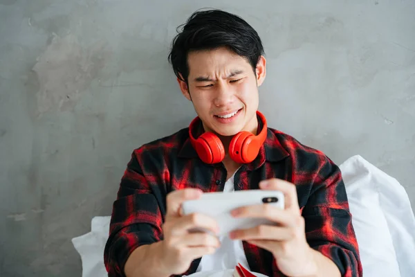 Asian young businessman playing mobile game on smartphone with serious looking.