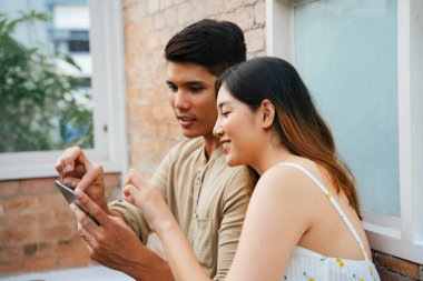 Asyalı çift restoranda akıllı telefondan dijital menüden yemek sipariş ediyor..