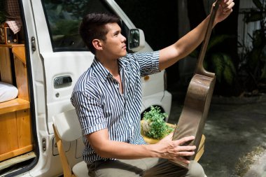 Arka bahçede akustik gitar ayarlayan Asyalı adamın portresi..