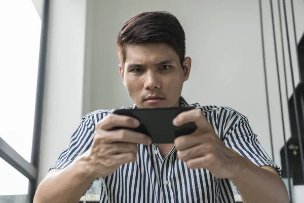 Asian Man Is Playing Mobile Game Seriously. Stock Photo, Picture