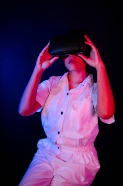 Asyalı kadın oyun veya 3D video ile etkileşen modern VR gözlük takıyor.