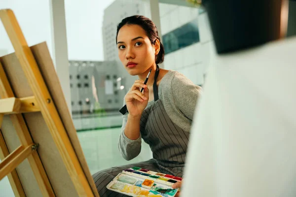 スタジオでのキャンバスイーゼル上の女性アーティストの絵画色油 — ストック写真