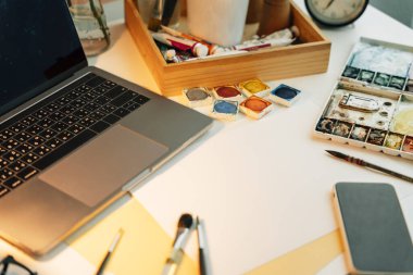 Üst görünüm - Renk boyama ekipmanları ve kağıt masanı ile çalışan sanatçı modeli.