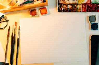 Üst görünüm - Renk boyama ekipmanları ve kağıt masanı ile çalışan sanatçı modeli.