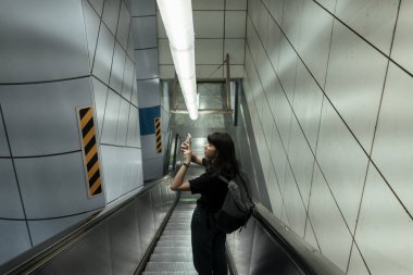Asyalı Taylandlı kadın metro istasyonuna yürüyen merdiven kullanıyor..