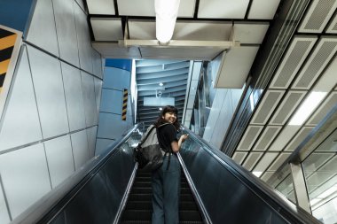 Asyalı Taylandlı sırt çantalı kadın yukarı çıkmak için yürüyen merdiven kullanıyor..