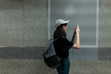 Asyalı Taylandlı sırt çantalı gezgin kadın metro metrosunun altında boş tahtanın önünde yürüyor - kopyalama alanı.