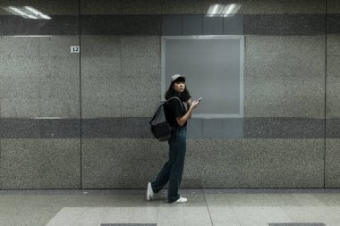 Asyalı Taylandlı sırt çantalı gezgin kadın metro metrosunun altında boş tahtanın önünde yürüyor - kopyalama alanı.