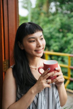 Asyalı kadın kahvaltıda bir fincan sıcak kahve içiyor..