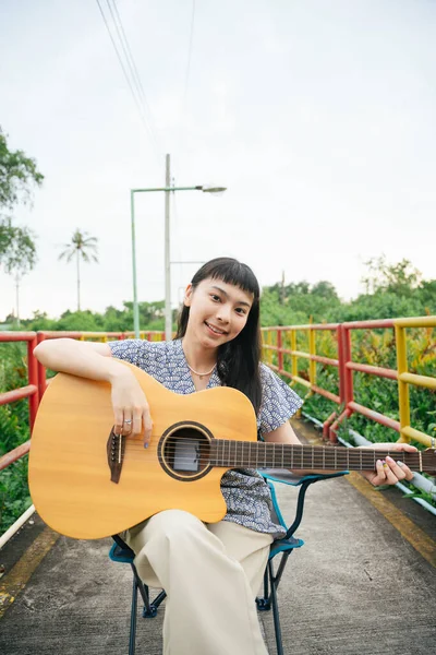 美丽的亚洲年轻女子在野外弹吉他的肖像 — 图库照片