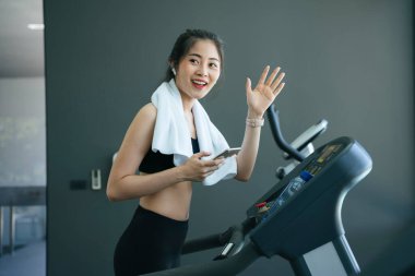 Sağlıklı Asyalı kadın spor salonundaki arkadaşına merhaba de..
