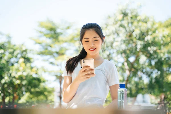 ランニング後のスマートフォンを使った健康的なアジア人女性 — ストック写真