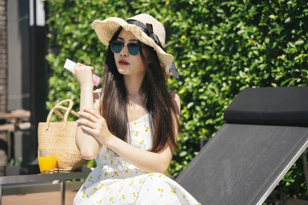 アジアの旅行者の女性は夏の季節に屋外で日焼け止めクリームを適用します — ストック写真