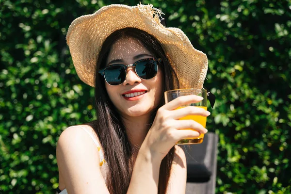 여름에는 안경을 모자를 오렌지 주스를 즐기는 아시아인 여행자의 — 스톡 사진