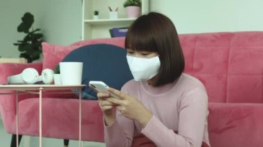 Genç Asyalı kısa saçlı, kısa saçlı, saçları kuru havluyla temizleyen ve akıllı telefon kullanan kadın..