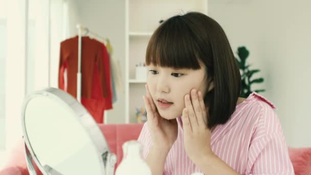 若いアジアの短いボブの髪型女性は 彼女の顔にスキンケアローションを適用しますミラーポータブル — ストック動画