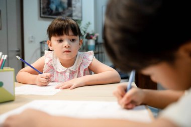 Küçük kız kardeşi, erkek kardeşinin ödevlerini mutfak odasında izliyor..