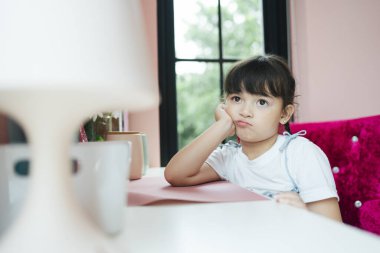 Küçük kız evde ödev yapmaktan yoruldu..