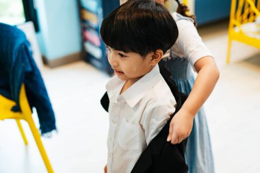 Hoş kız kardeşi, erkek kardeşine resmi bir takım elbise giydirmeye yardım ediyor..