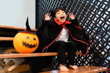 Cadılar Bayramı kostümü giymiş küçük bir çocuk ve balkabağı balonu..