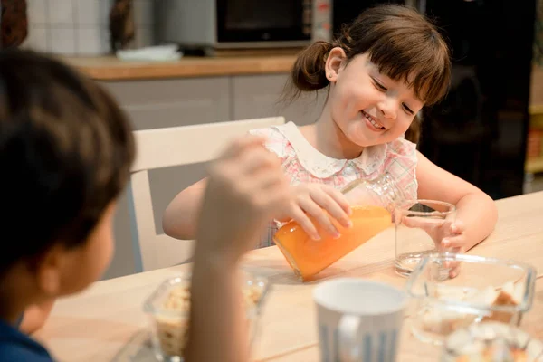 Hermana Vertiendo Jugo Naranja Para Servir Hermano Cocina —  Fotos de Stock