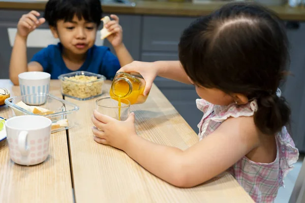 Sister Pouring Orange Juice Her Brother Kitchen — Stock Photo, Image