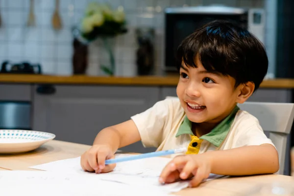 Alegre Asiático Chico Haciendo Tarea Cocina Mesa —  Fotos de Stock