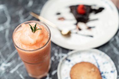 Yakın çekim - Bardakta Tayland çayı milkshake 'i ve çikolatalı kek ayrıca beyaz tabakta çıtır kurabiye. Tatlı yemeği..