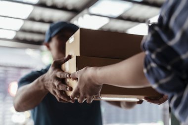Görevli yerel teslimatçı müşterilerine karton kutuları teslim ediyor..