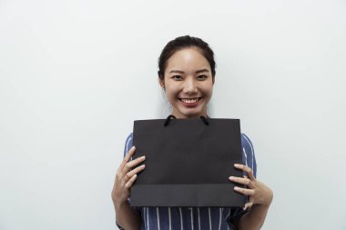 Neşeli ve neşeli Asyalı kadın elinde siyah bir alışveriş çantası, beyaz arka planda iki el izole edilmiş..