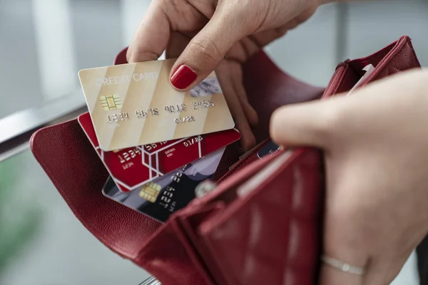 Hand of woman pulling out credit card from red purse - Shopping concept.