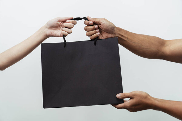 People hands holding giving black shopping paper bags over white background.