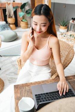 Laptop ve akıllı telefonla çalışan güzel Asyalı bir kadın..