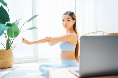Güzel, sportif bir kadın çevrimiçi yoga dersi veriyor. Dizüstü bilgisayarda yoga dersi izliyor..