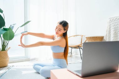 Güzel, sportif bir kadın çevrimiçi yoga dersi veriyor. Dizüstü bilgisayarda yoga dersi izliyor..