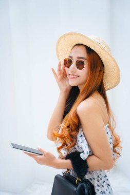Güzel Asyalı gezgin kadın güneş gözlüğü takıyor ve akıllı telefon kullanıyor..