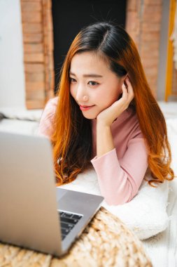 Güzel Asyalı kadın evde dizüstü bilgisayarla çalışıyor..