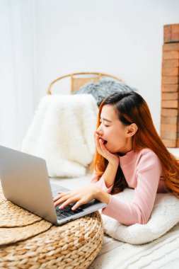 Güzel Asyalı kadın dizüstü bilgisayarla uzun süre çalıştıktan sonra esniyor..