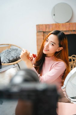 Kameranın önünde sosyal medya için kozmetik video şovu yapan güzel bir kadın..