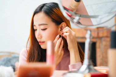 Güzel Asyalı kadın evde küpe takıyor..