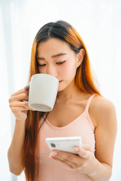 Bela Jovem Ásia Mulher Segurando Xícara Café Usando Smartphone Isolado — Fotografia de Stock