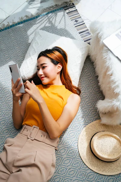 Bonita Jovem Mulher Asiática Que Coloca Travesseiro Usando Smartphone Casa — Fotografia de Stock