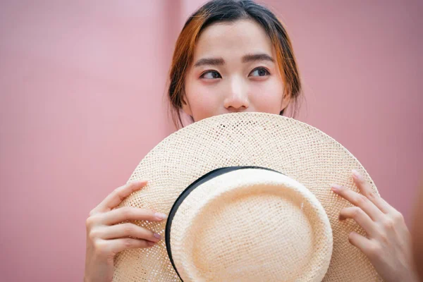 ピンクの背景に藁帽子を持つ美しいアジアの女性の肖像画 — ストック写真